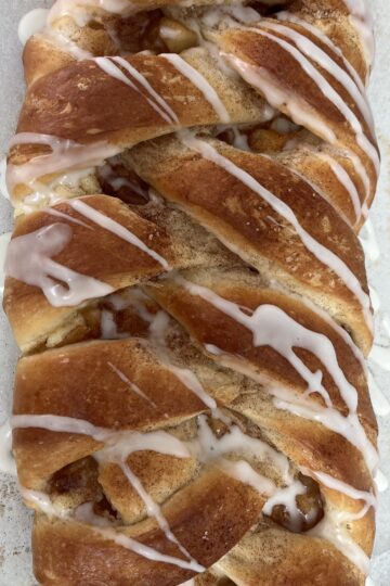 A picture of an apple cream cheese Danish braid with glaze drizzled on top.