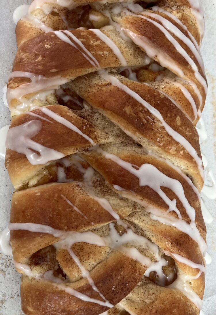 A picture of an apple cream cheese Danish braid with glaze drizzled on top.